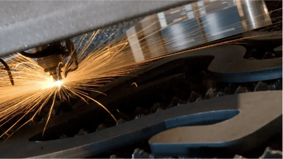 Fiber laser cutting a steel sheet, showing the narrow kerf channel left along the cut line